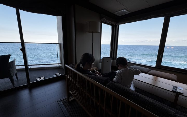 部屋から海を見る母子、夕方