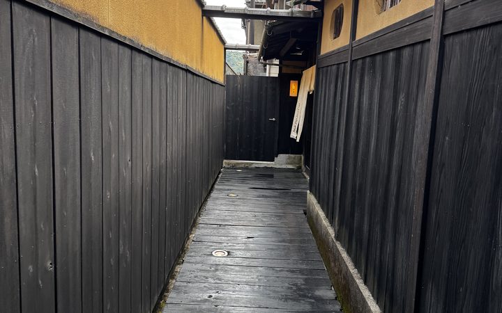 京都の細い路地、黄色い壁と黒い板塀